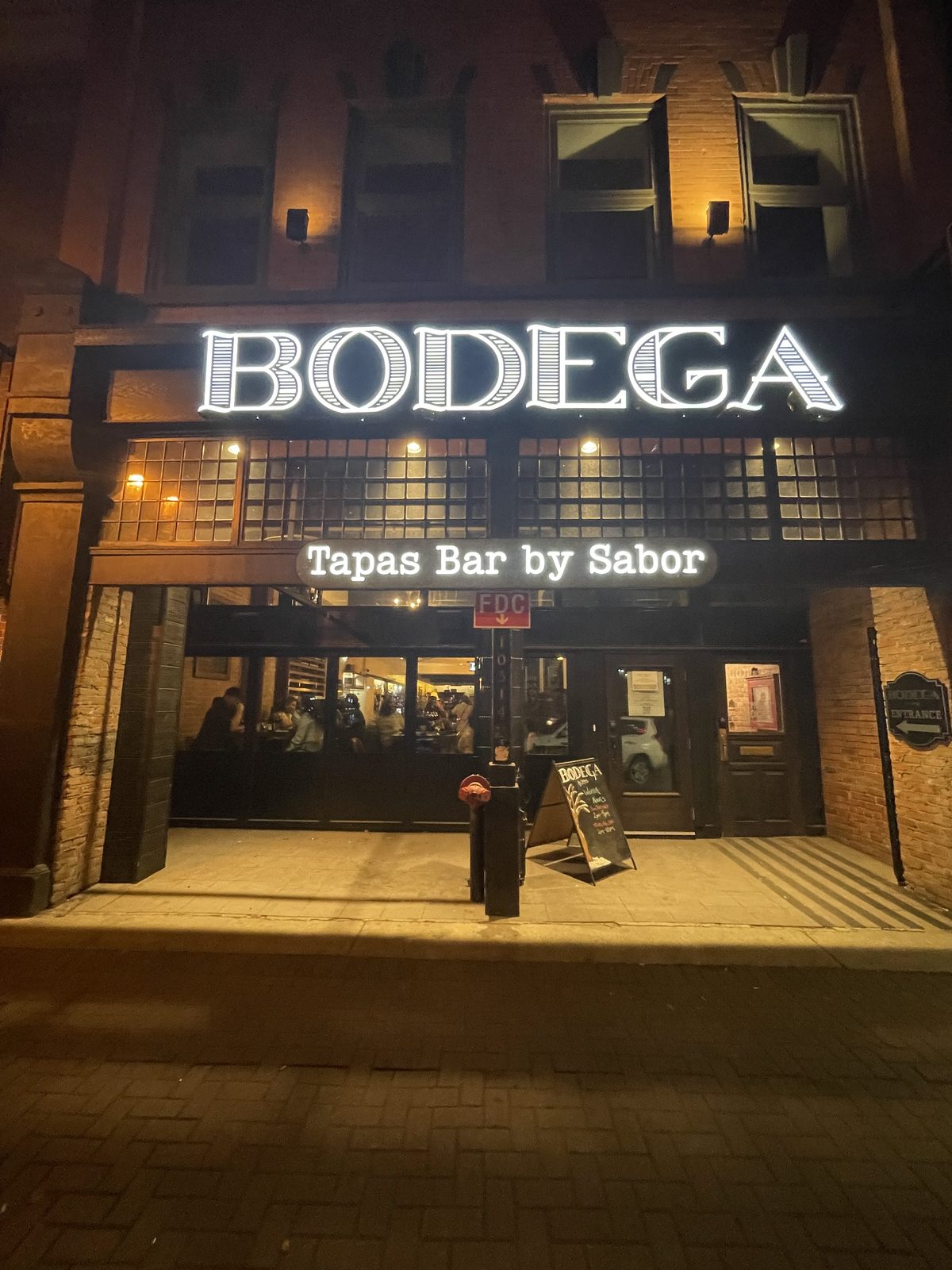 Illuminated Bodega channel letter sign on a downtown restaurant at night
