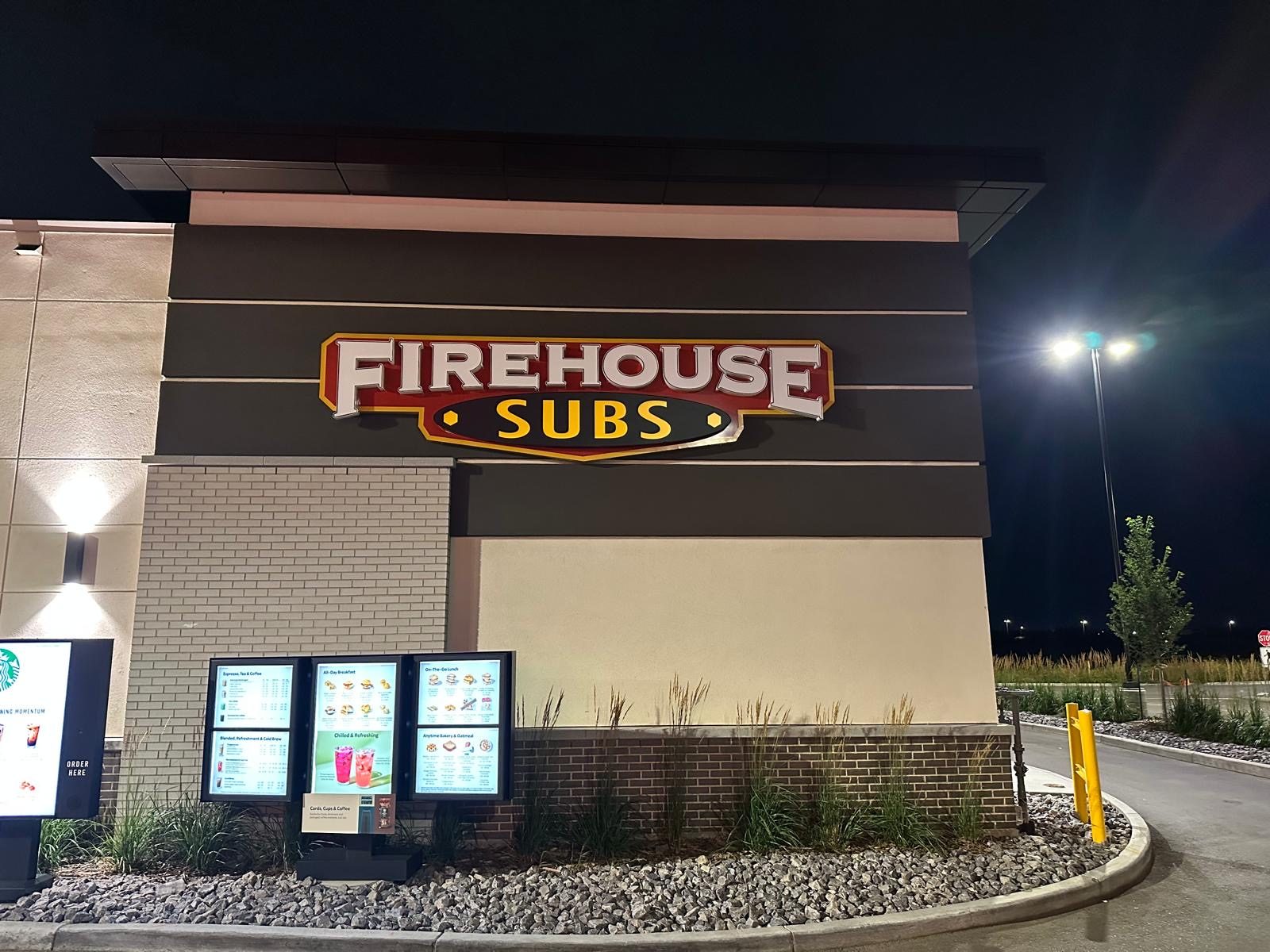 Firehouse Subs illuminated channel letter sign on a building exterior at night