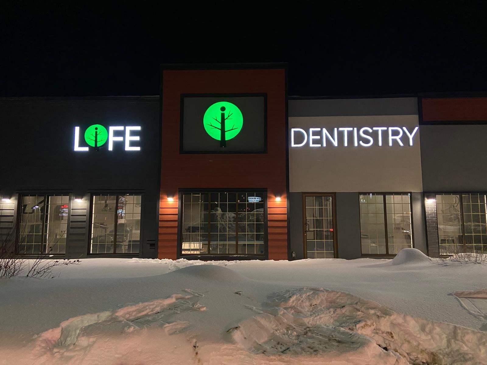 LIFE Dentistry illuminated channel letters on a building at dusk