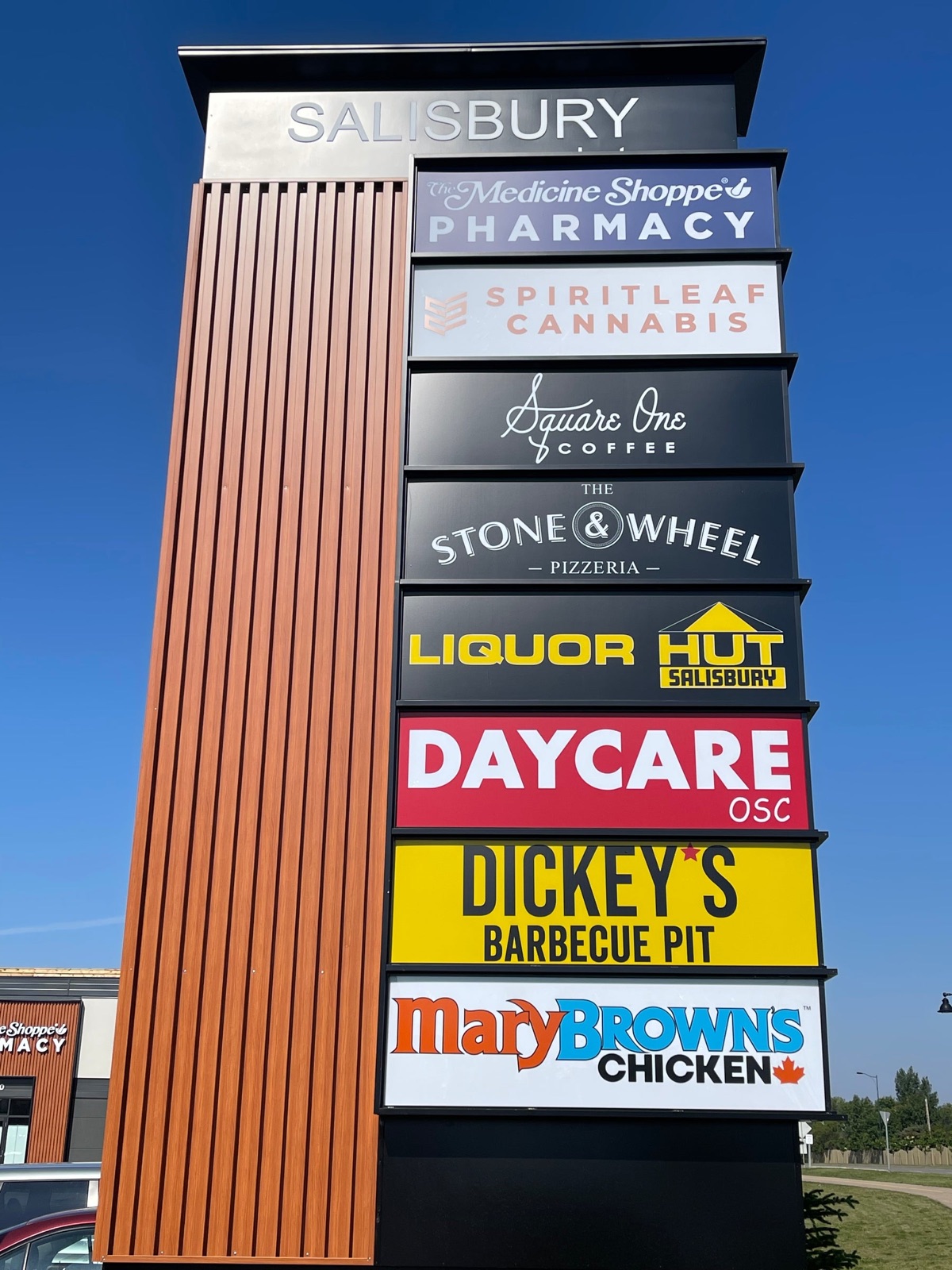 Tall multi-tenant retail pylon sign with stacked illuminated tenant panels