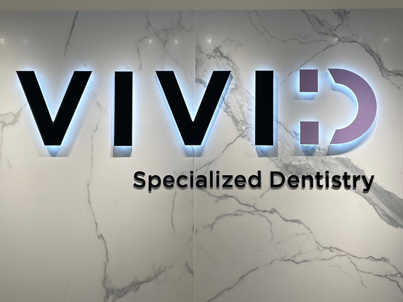 Large VIVID Specialized Dentistry dimensional letters mounted on a stone building facade