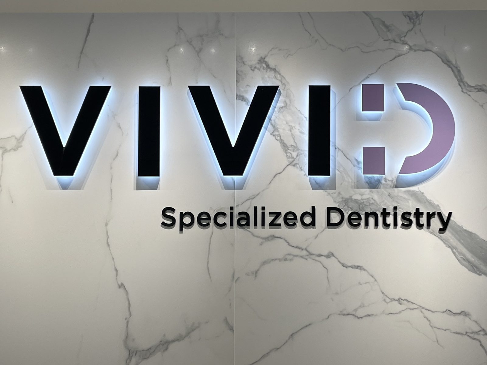 VIVID Specialized Dentistry halo-lit channel letters on a marble feature wall